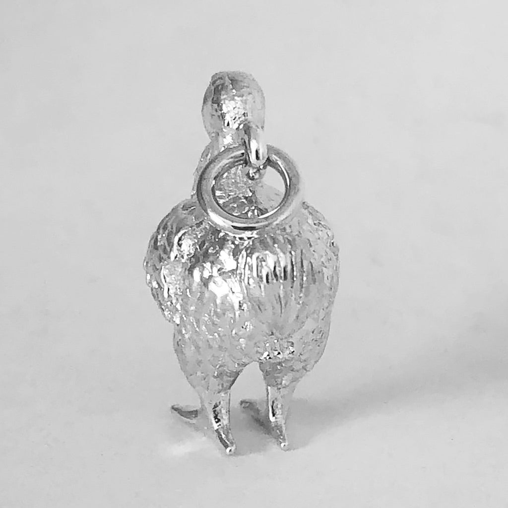 Rear view of sterling silver dodo charm on a grey background