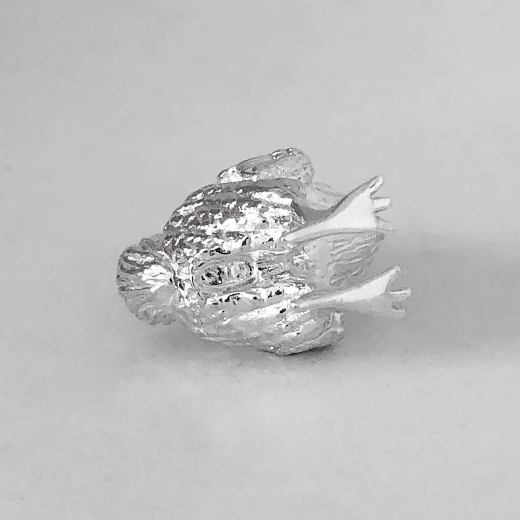 Sterling silver dodo charm viewed from underside on a grey background