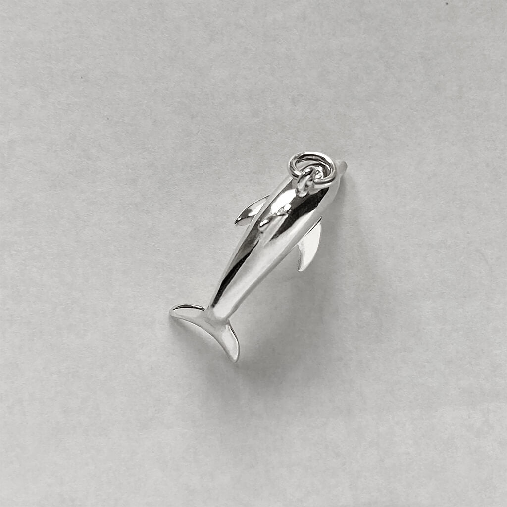 Sterling silver dolphin charm viewed from above on a grey background