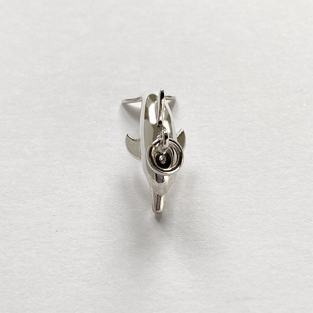 Sterling silver dolphin charm viewed from above on a grey background