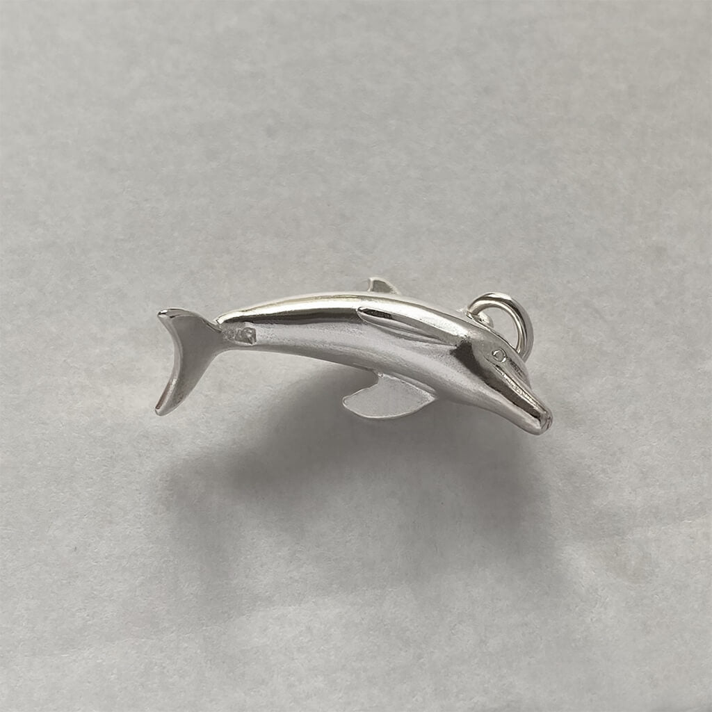 Sterling silver dolphin charm viewed from underneath on a grey background