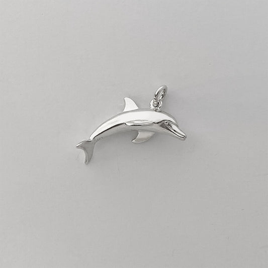 Sterling silver dolphin charm on a grey background