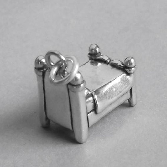 back side view of silver bed charm on grey background