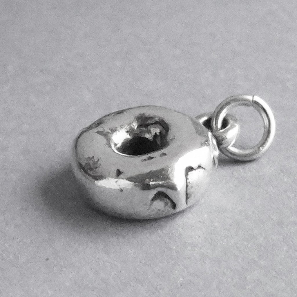 Sterling silver donut charm on a grey background