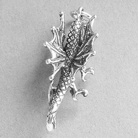 back of a silver dragon charm on a grey background
