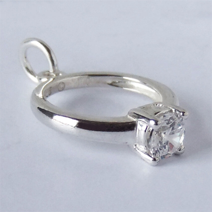 silver and crystal engagement ring charm on light grey background