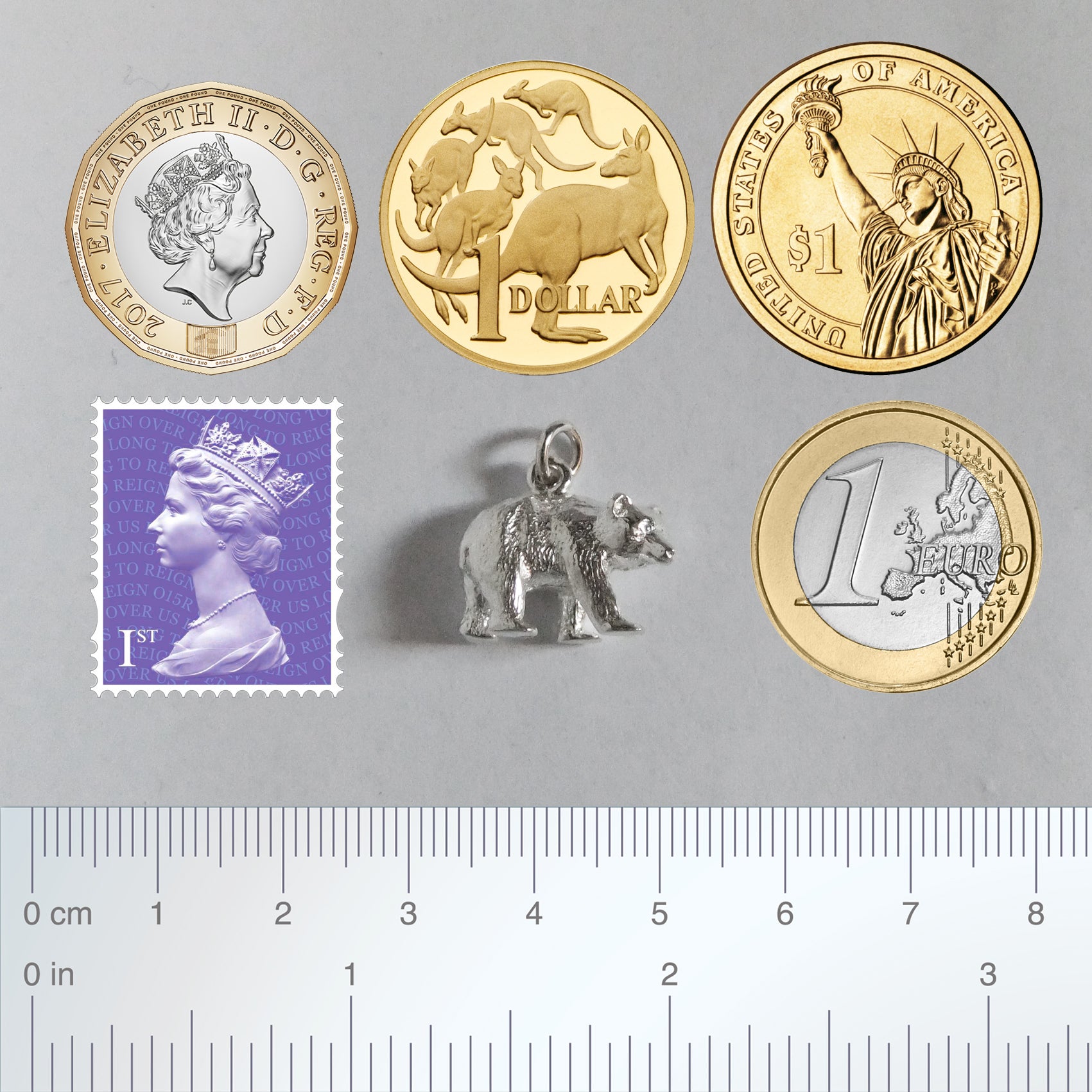 bear charm with coins ruler and postage stamp for scale