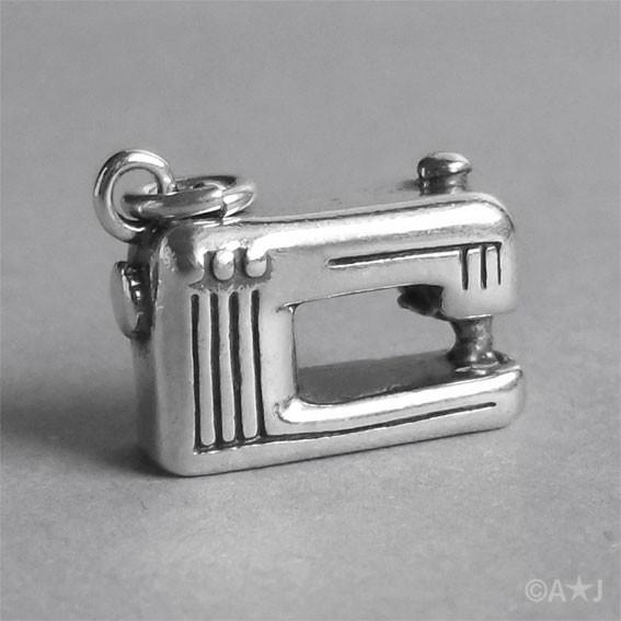 silver sewing machine charm on a grey background