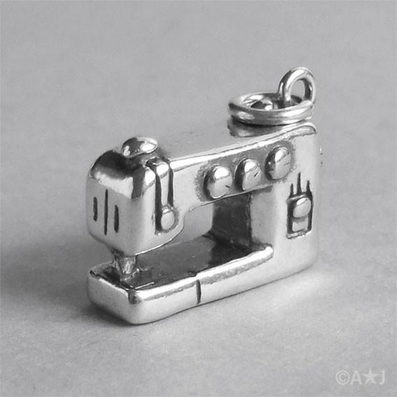 silver sewing machine charm on a grey background