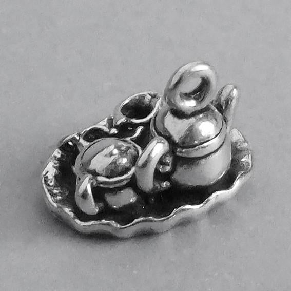 silver tea set charm viewed from above on a grey background