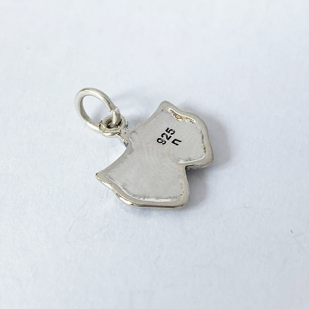 back view of silver theatre masks charm on grey background